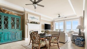 Un vaste espace de vie comprenant une table à manger, des chaises, un téléviseur et une vue sur la mer.