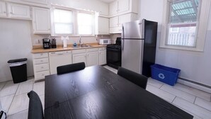 Een keuken met witte kastjes, een zwarte koelkast, een magnetron en een koffiezetapparaat.