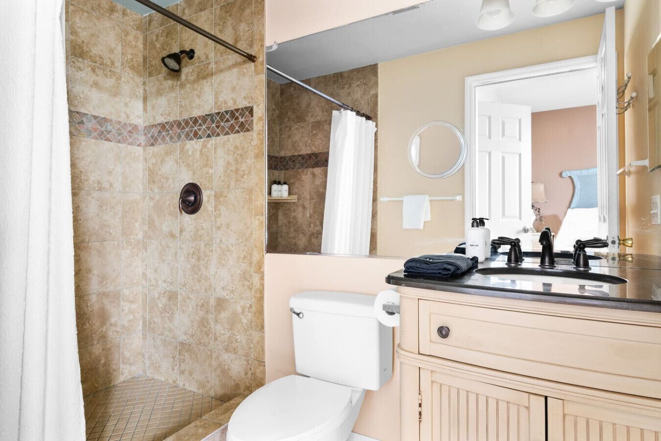 A bathroom with a shower, toilet, and vanity with a mirror.