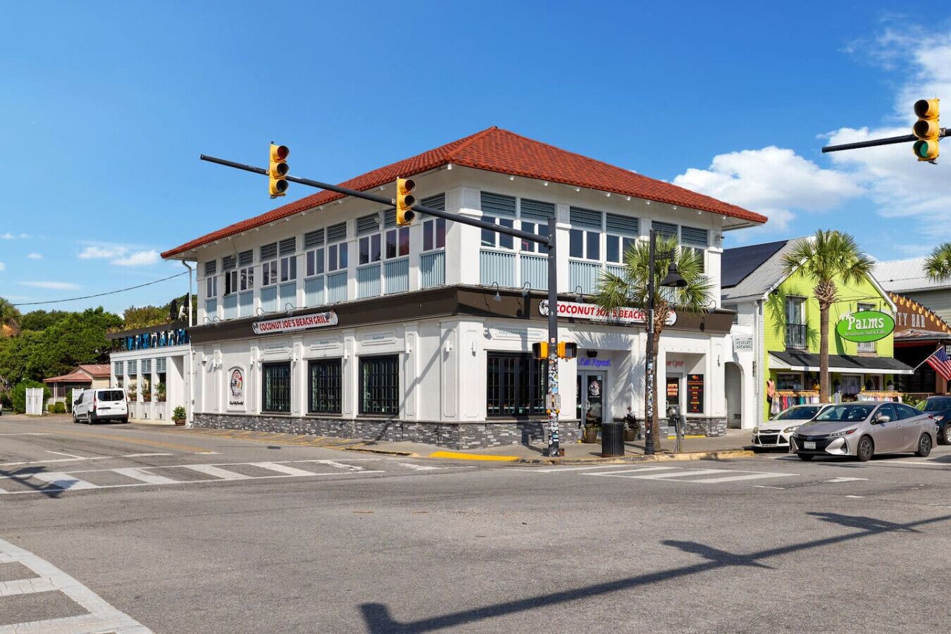 A two-story building with a red-tiled roof, a balcony, and a sign for Coconut Joe's Beach Grill.