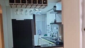 A modern kitchen with a built-in refrigerator, a dining table set with plates and glasses, and a hanging light fixture above the counter. - Beautiful apartment with a spectacular view (Cali)