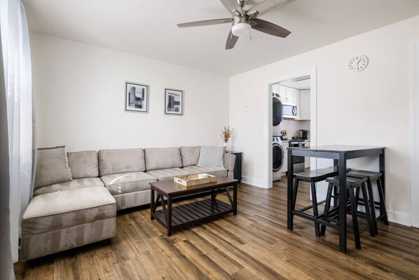 A modern living room with a sofa, coffee table, and a dining area with chairs. - Cozy 2BR Getaway Minutes to Downtown - Dayton A (North Charleston)