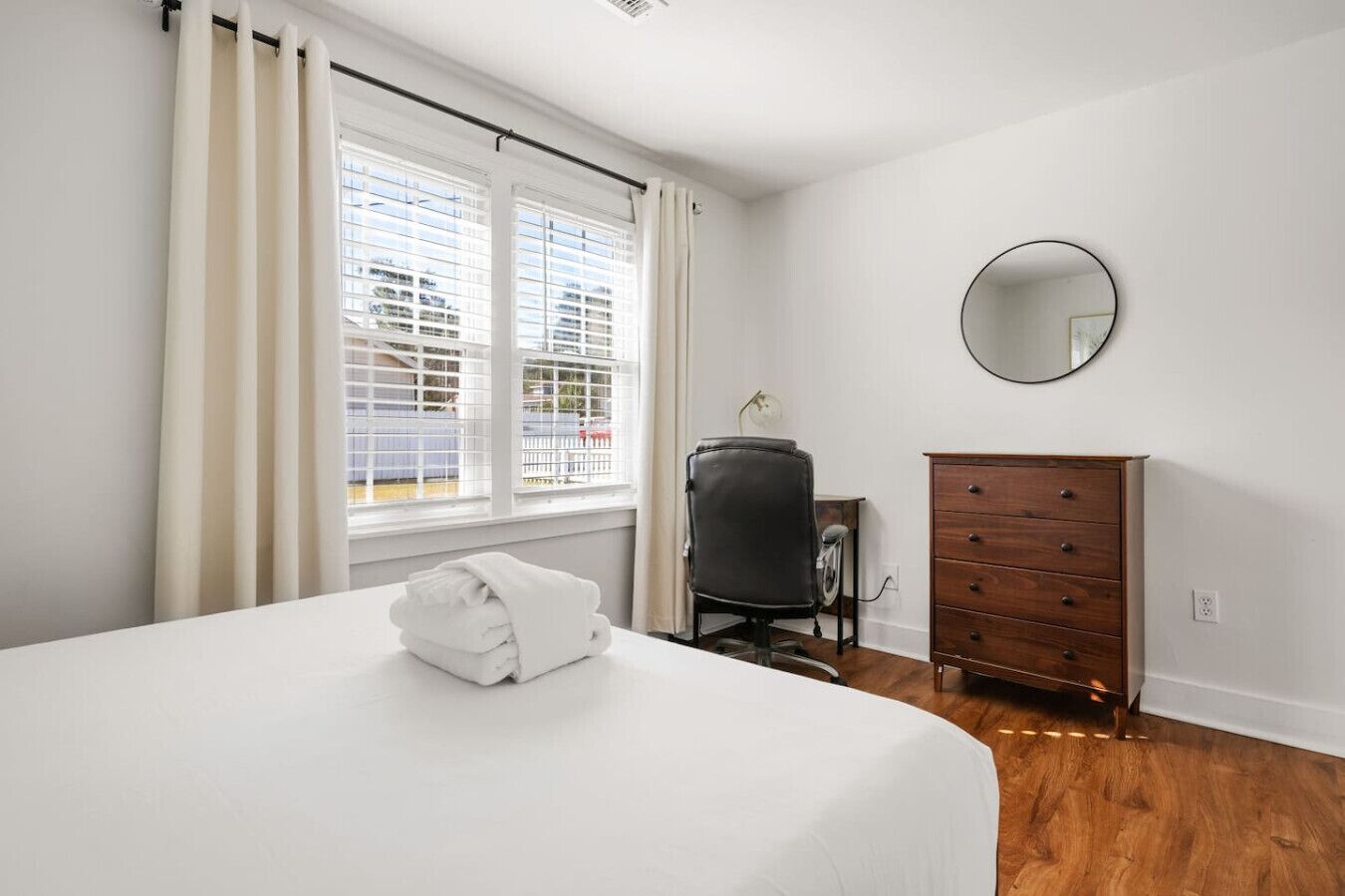 Un dormitorio con cama, cómoda, silla y ventana con persianas.
