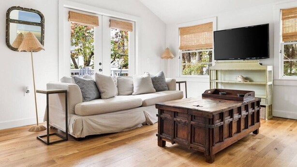 A living room with a sofa, wooden coffee table, and a television on the wall. - Beach Maverick - 3 BR 2 Bath 1 Block to Center St! (Folly Beach)