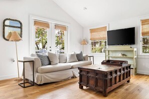 A living room with a sofa, wooden coffee table, and a television on the wall. - Beach Maverick - 3 BR 2 Bath 1 Block to Center St! (Folly Beach)