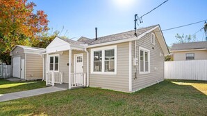 Ein Bungalow mit Veranda, Garage und einem eingezäunten Garten.