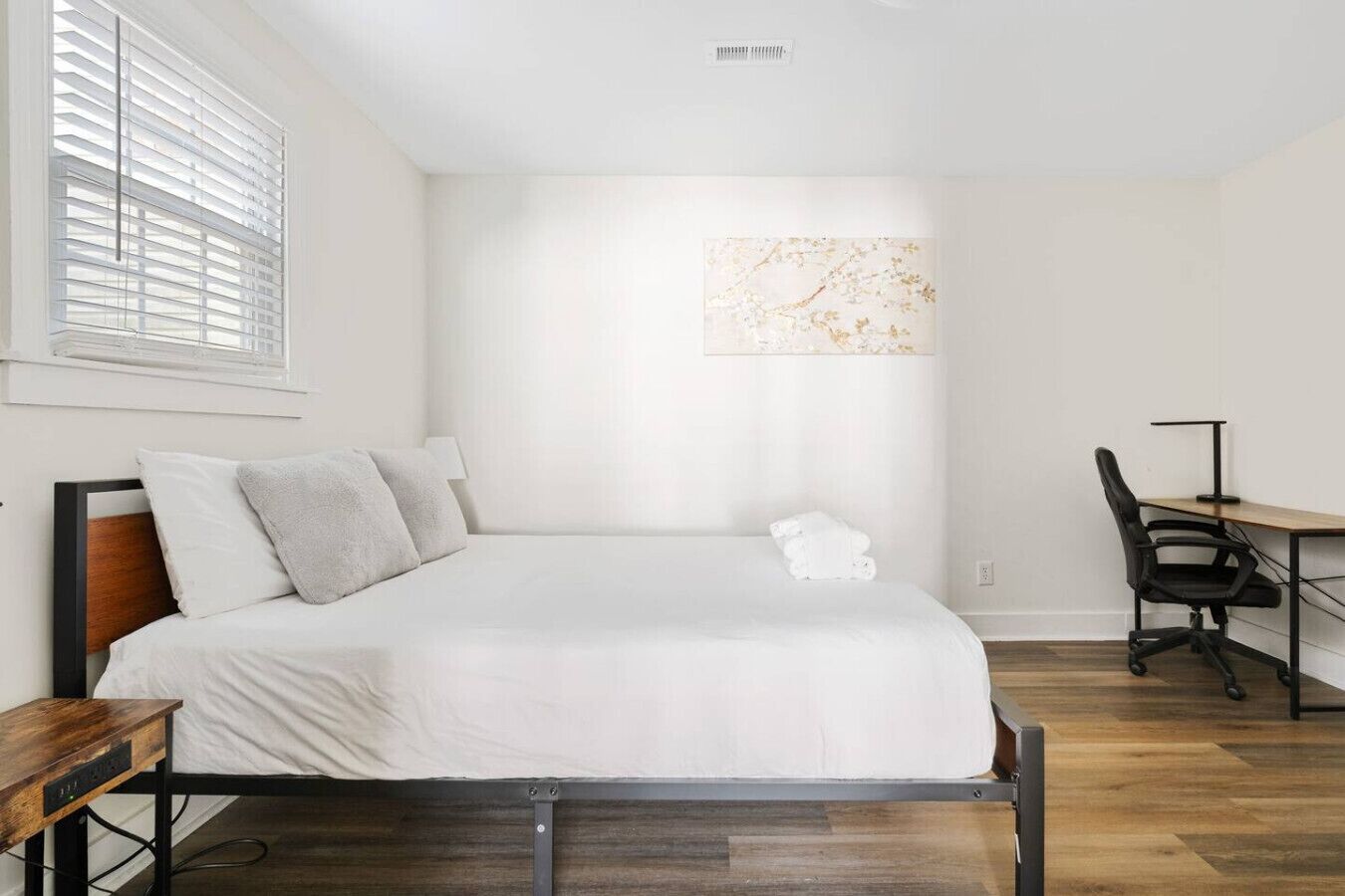 A bedroom with a bed, a desk, and a chair.