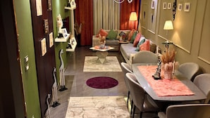 Un salon moderne avec un canapé, une table à manger et des chaises. Les murs sont décorés et un lustre est suspendu au plafond.
