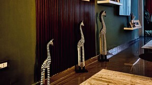 Un hall d  ’entrée avec un mur en bois foncé, un tapis à motifs et des sculptures décoratives représentant des zèbres.