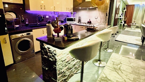 Une cuisine moderne dotée d’un îlot central, de tabourets de bar, d’un lave-linge et d’un coin repas offrant une vue agréable.
