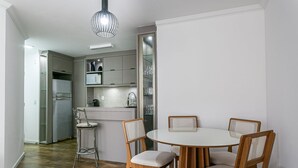 Una cucina moderna con zona pranzo, che include un tavolo rotondo, sedie in legno, un frigorifero integrato e una lampada a sospensione.