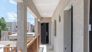 Un couloir avec une rambarde en bois, un paillasson et une porte.