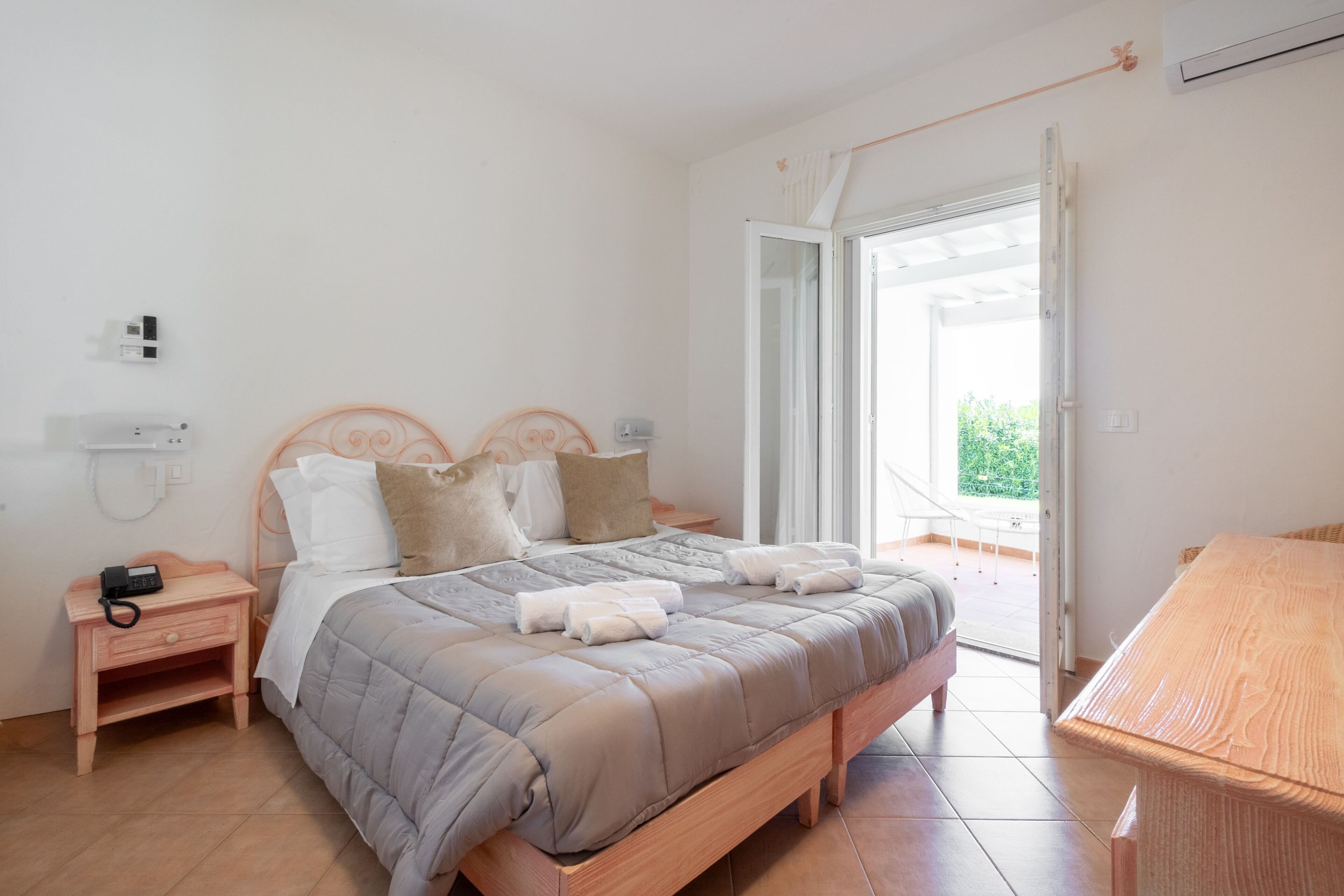 Un dormitorio con cama, mesitas de noche, teléfono y vistas al exterior.