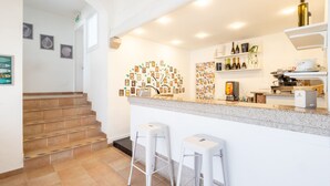 A modern kitchen with a granite countertop, white bar stools, and a wall art installation. - Hotiday Baja Sardinia Seaside (Baja Sardinia)