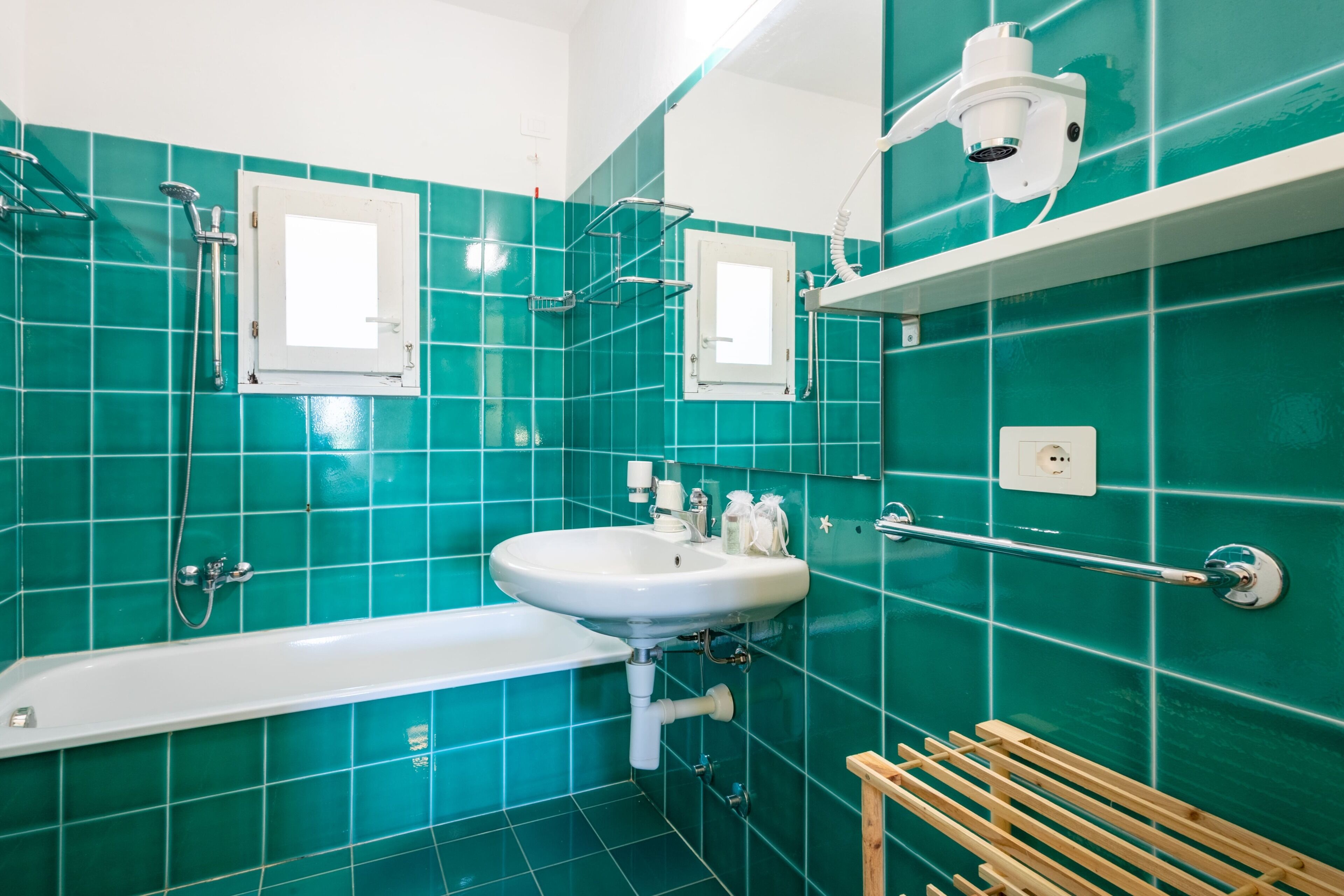 A bathroom with a white bathtub, a sink, a mirror, and a shower.