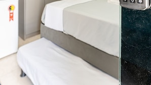 Habitación de hotel con cama, escritorio con computadora, televisor montado en la pared y minibar.