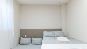 Ein schlicht eingerichtetes Schlafzimmer mit Bett, Kissen und Nachttisch.