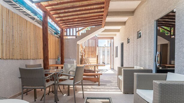 Eine Außenpatio-Terrasse mit Korbmöbeln, einem Holz-Pergola und Blick auf die umliegende Landschaft.