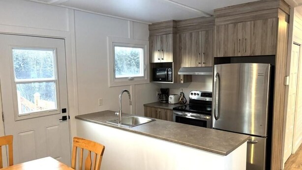 Une cuisine moderne avec des meubles en bois, des appareils en acier inoxydable, un four encastré et un grand îlot central doté d’un évier.