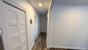 Un couloir doté d’un plancher en bois, de murs blancs et d’une porte blanche ornée d’une étoile.