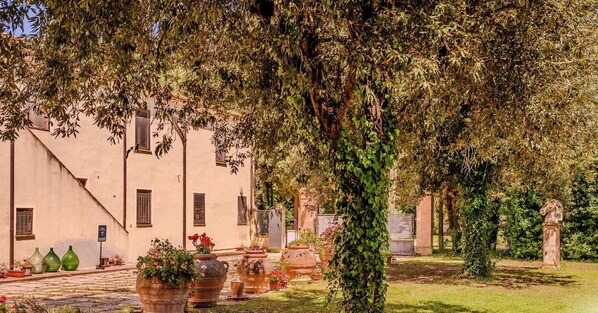A courtyard with a building, potted plants, and a statue. - Hotiday Grosseto Podere (Grosseto)