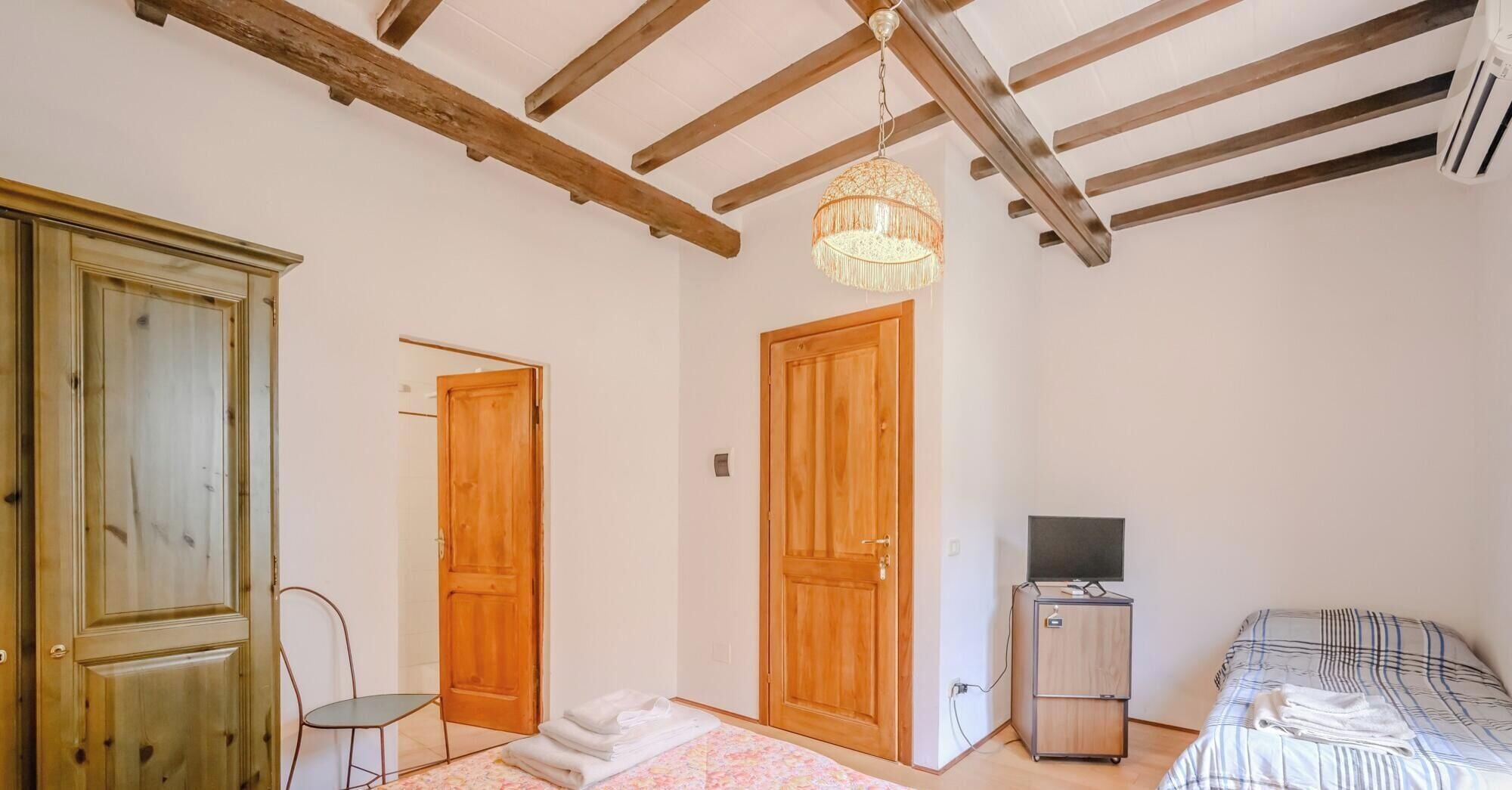 Una habitación con una cama, televisión, armario y dos puertas de madera.