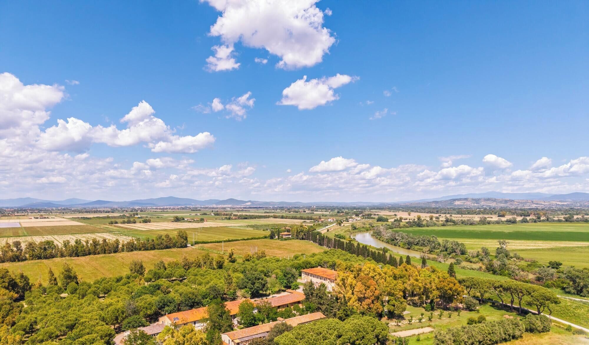 A rural landscape with fields, trees, and a river.