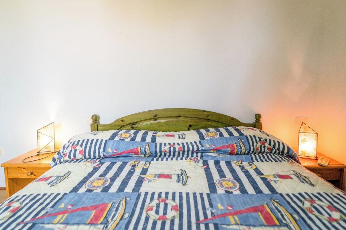 Una cama con colcha a rayas, dos lámparas de noche y un cabecero de madera.