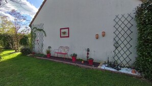 A building with a white exterior, a red-framed picture, and potted plants. - Bed and breakfast. Pets allowed. (Marcilly-en-Villette)