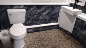 Een badkamer met toilet, wastafel en een marmeren wand.