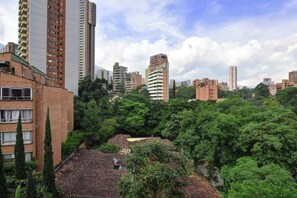 A high-rise building with multiple floors, surrounded by dense greenery and other high-rise buildings in the background. - Ayamonte 404 (Medellín)