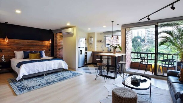 Een moderne slaapkamer met een groot bed, een eethoek en een balkon met uitzicht.