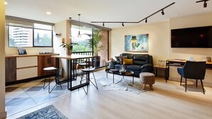 Een moderne woonkamer met een zwarte leren bank, een salontafel, en een eethoek met een kleine tafel en stoelen.