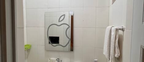 A small, compact bathroom with a white sink, a toilet, and a mirror with an apple logo.