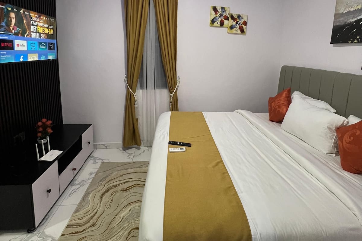 A modern bedroom with a bed, a TV, and a wall-mounted air conditioner.