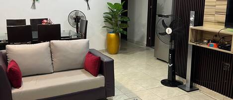 A modern living room with a sofa, a glass coffee table, and a dining area with chairs.