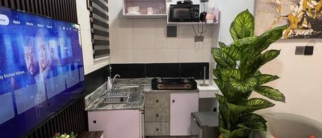 A modern kitchen with a built-in TV, a dining area with a sofa, and a large potted plant.