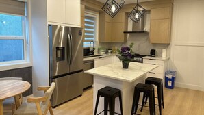 A modern kitchen with a central island, stainless steel appliances, and pendant lighting. - Pristine Brand New Duplex, Prime Location! (Vancouver)