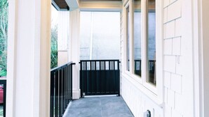 A covered outdoor area with a black railing, a concrete floor, and a view of the street. - Pristine Brand New Duplex, Prime Location! (Vancouver)