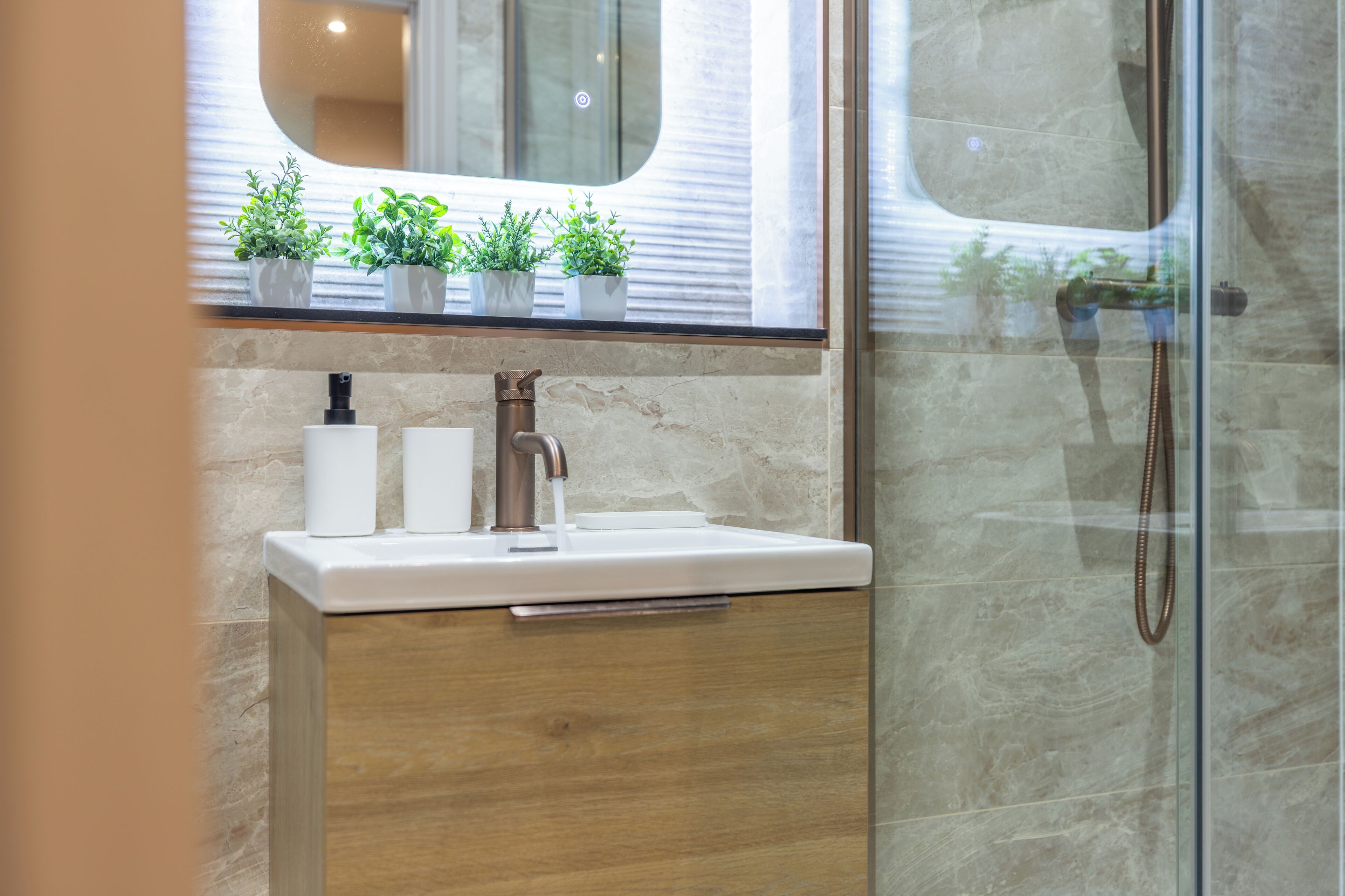 A bathroom with a marble sink, a wooden cabinet, and a glass shower enclosure.