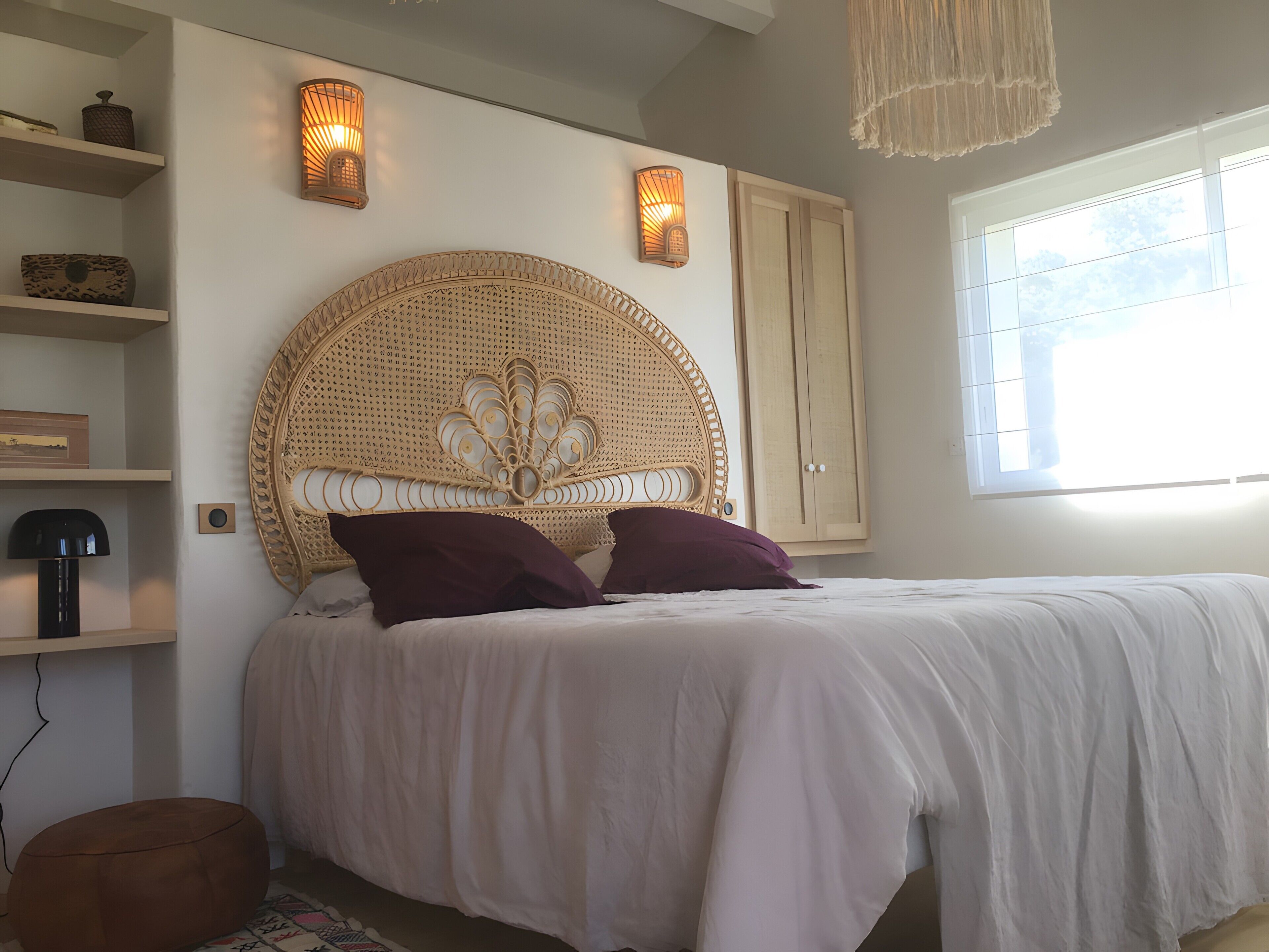 Un dormitorio con una cama grande, dos lámparas de pared, un armario y una ventana.