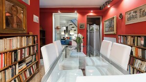 Un salon moderne avec une table basse en verre, des canapés blancs et des étagères remplies de livres.
