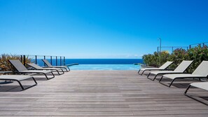 A wooden deck with lounge chairs facing a pool and the ocean. - Lyra Luxury Savoy Monumentalis by LovelyStay (Funchal)