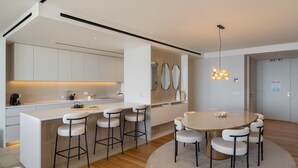 Een moderne keuken met een centraal eiland, barkrukken en een ronde eettafel.