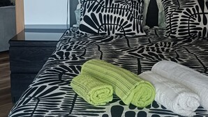 Un dormitorio con una colcha estampada, una toalla verde y una toalla blanca.