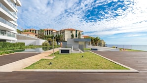 Ein moderner Wohnkomplex mit Schwimmbad, Holzterrasse und Meerblick.