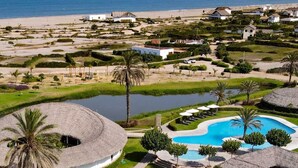 A resort with a large pool, palm trees, and a beach.