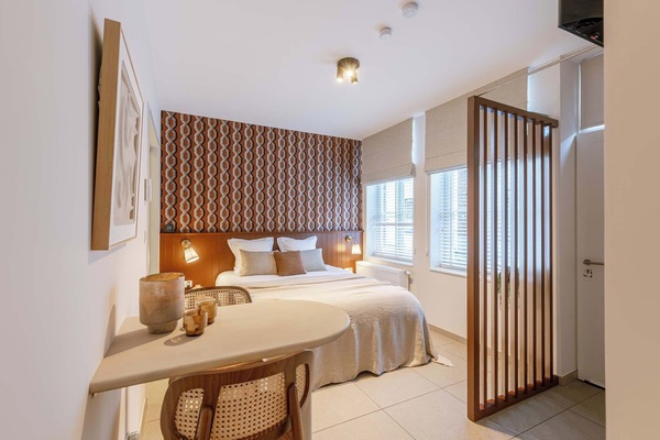 Atmospheric bedroom with a double bed and a dedicated seating area, featuring retro-inspired wall decor.