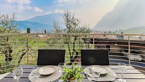 Une table dressée pour deux personnes, avec vue sur les montagnes et le paysage urbain.