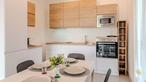 Une cuisine moderne avec des meubles blancs, un four encastré et un four à micro-ondes.